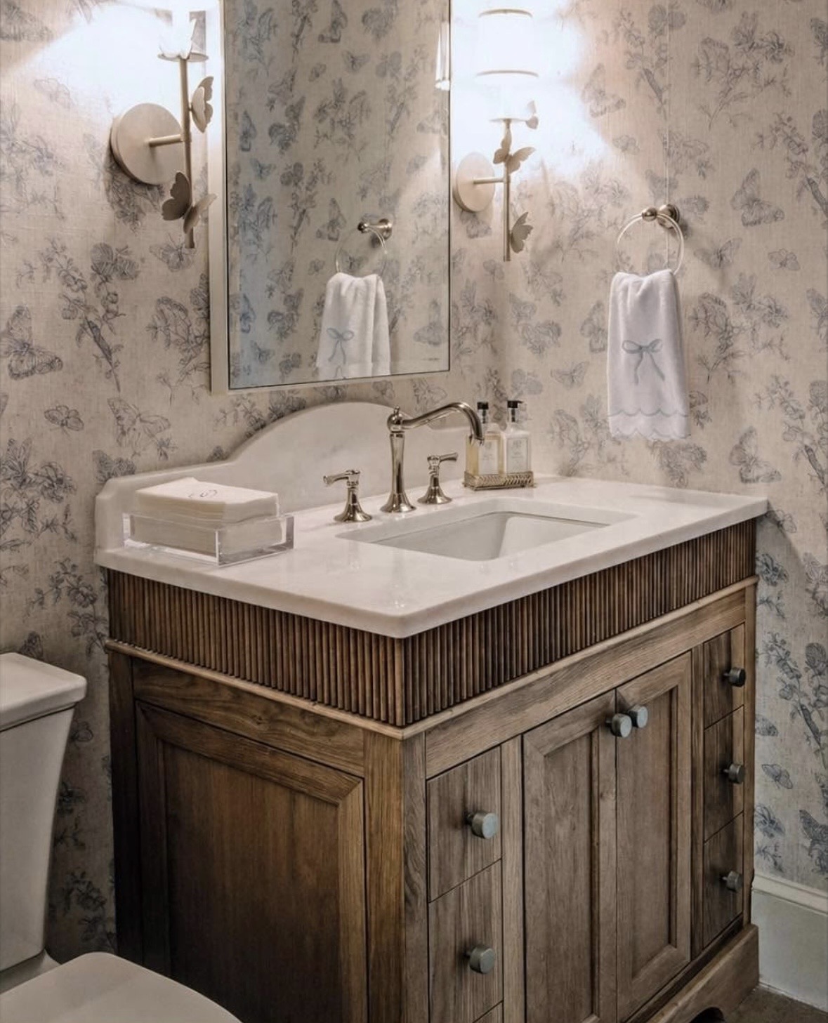 Fluted walnut vanity with marble countertop and traditional faucet