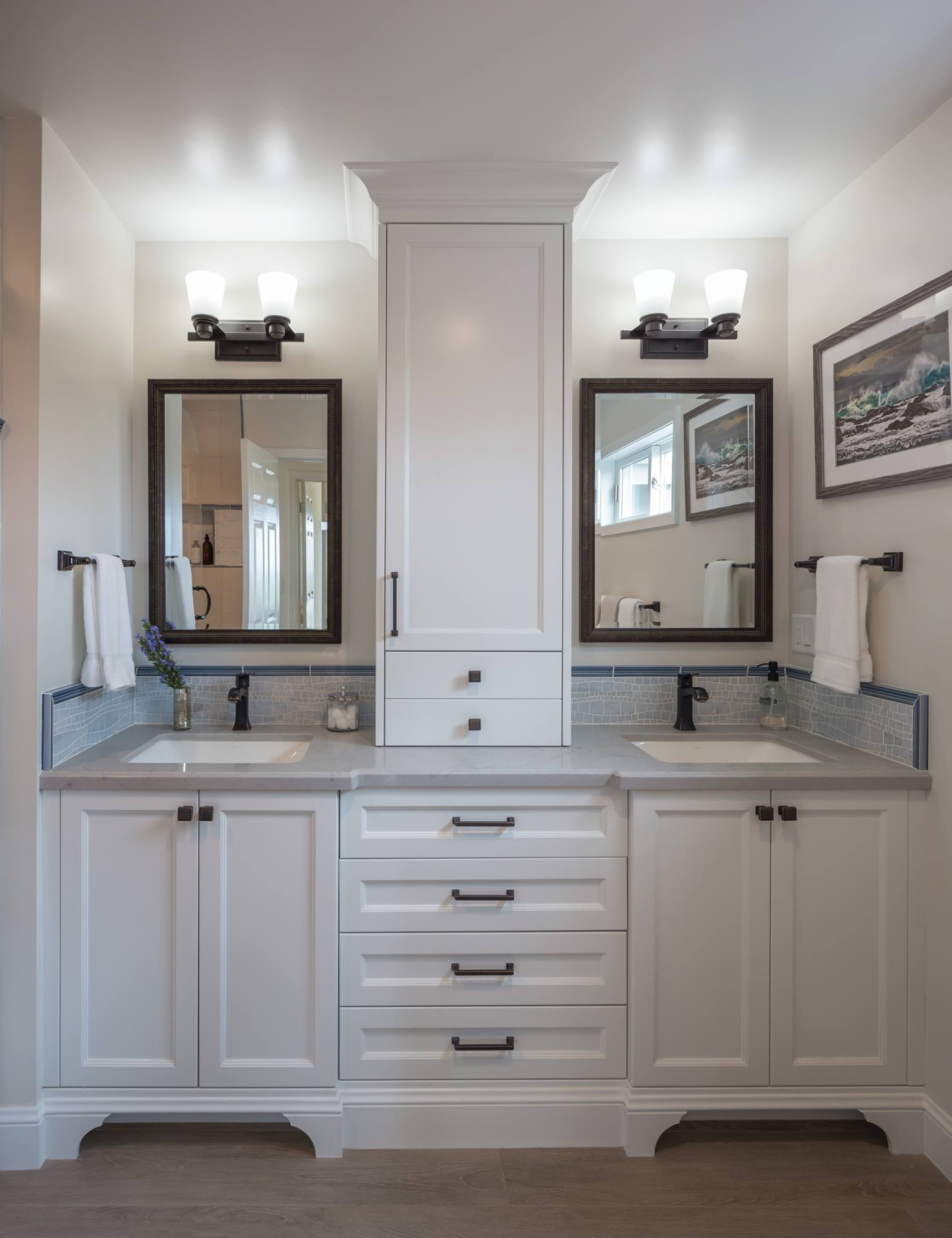 White double vanity with center tower cabinet and tile backsplash