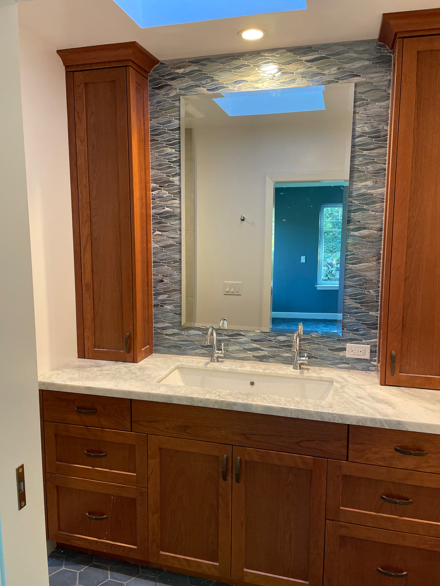 Cherry wood vanity with linen towers and glass mosaic backsplash