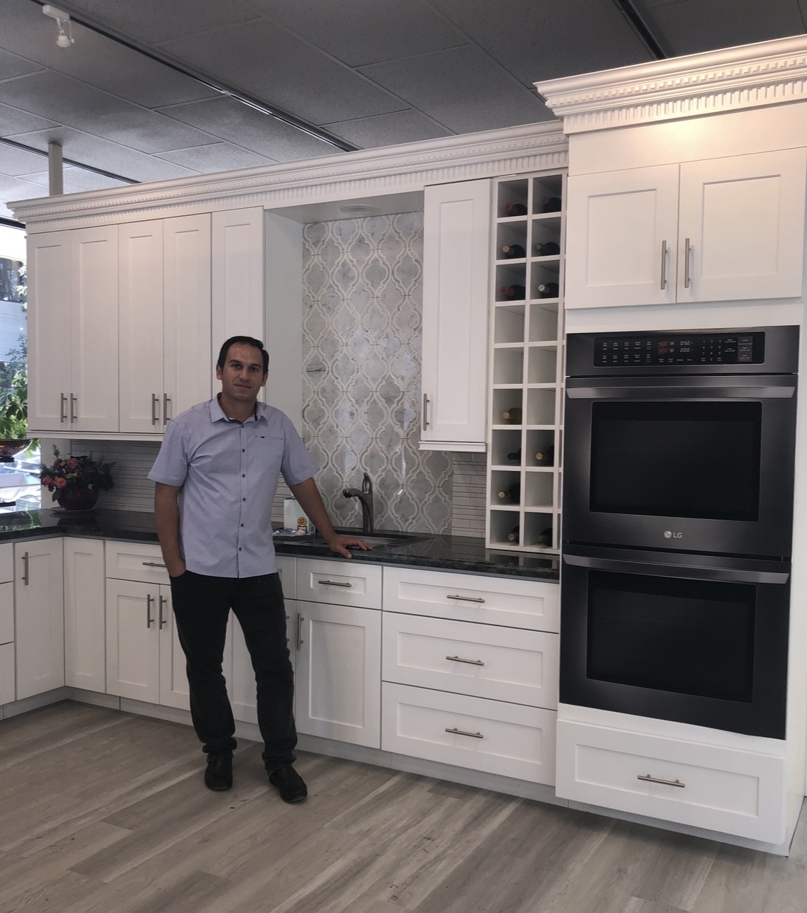 Elbron in a showroom with white shaker cabinetry, wine cubbies, and double wall ovens