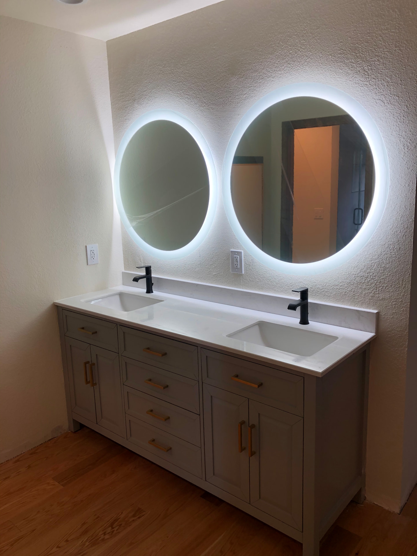 Greige double vanity with quartz top and backlit round mirrors