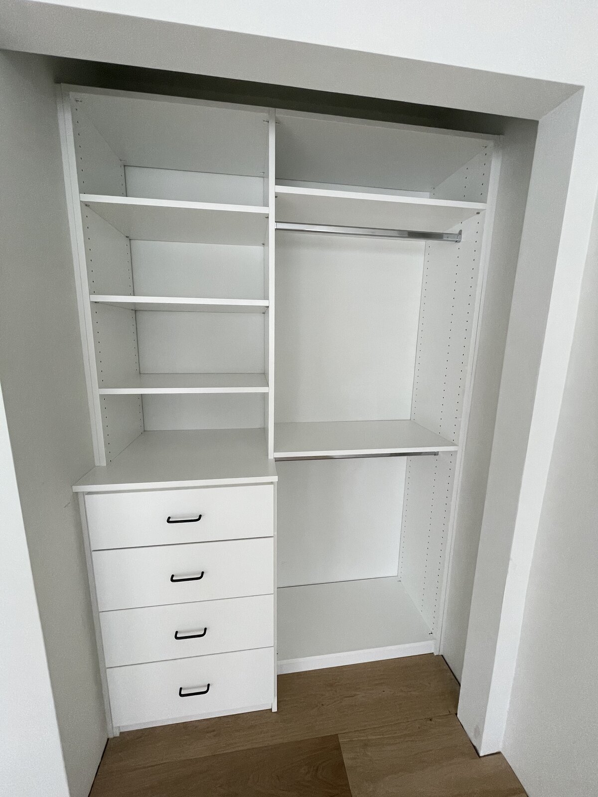 Custom white closet cabinetry with drawers and hanging space