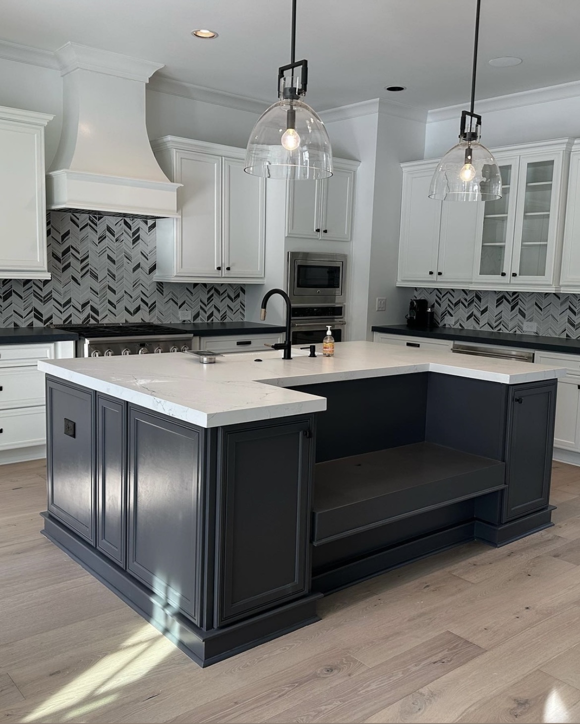 White cabinets with charcoal island and chevron marble backsplash